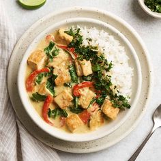 a white plate topped with rice and tofu next to a bowl of green vegetables