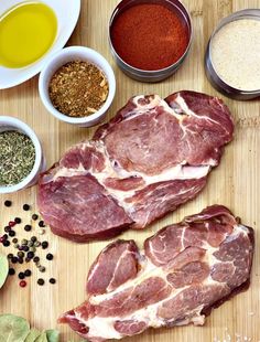 some meats are laying out on a cutting board next to spices and seasonings