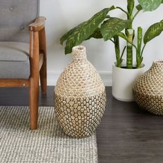 two vases sitting on top of a wooden floor next to a chair and potted plant