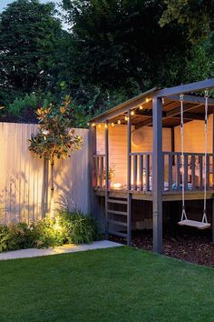 a backyard with a deck, swing set and lights on the side of the house