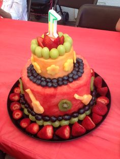 a watermelon birthday cake with fruit on top and one candle in the middle