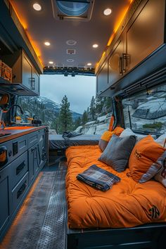 an orange bed in the back of a van with mountains in the background and lights on