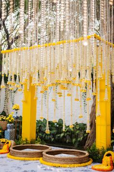 an outdoor ceremony with yellow and white decorations on the ground, hanging from strings in the air