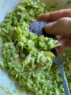 a person is scooping broccoli out of a bowl