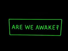 a neon green sign that says are we awake? in the middle of black background