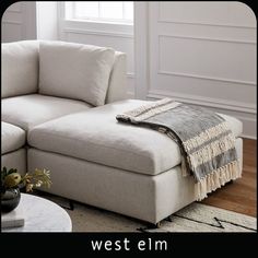 a living room with a sectional couch and coffee table in front of a white wall