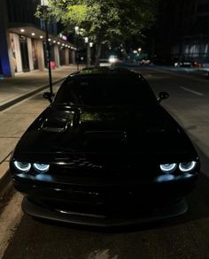 a black car is parked on the street at night