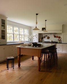 a kitchen with an island and stools in front of the counter top, along with two windows