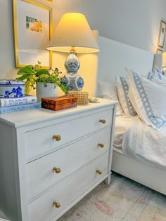 a white bed with blue and white decor on the night stand next to two lamps