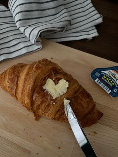 a croissant with butter on it sitting on a cutting board next to a knife