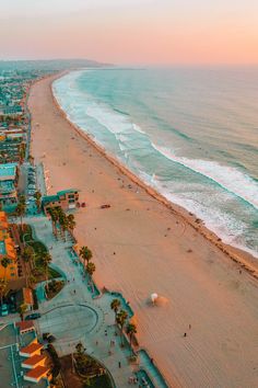 an aerial view of the beach and ocean at sunset, with buildings in the foreground