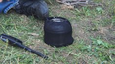 a black bag sitting on top of a grass covered field next to a person's foot