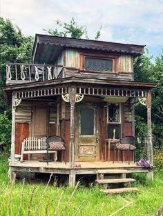 an old wooden house sitting on top of a lush green field