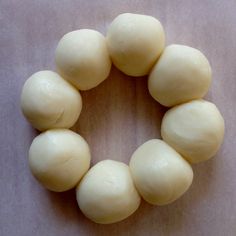 doughnuts arranged in the shape of a wreath on a wooden surface, ready to be baked