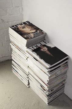 a stack of magazines sitting on top of each other next to a white brick wall