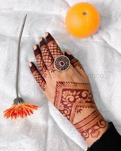 henna tattoo on hand next to an orange