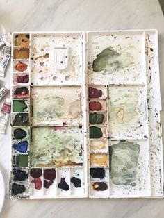 an artist's palette with watercolors and paintbrushes on a table