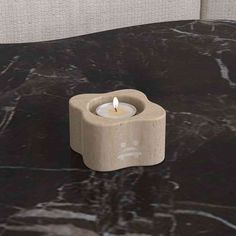 a small candle sitting on top of a black marble table next to a white wall