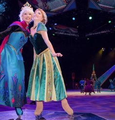 two women dressed as frozen princesses standing on stage with their arms around each other