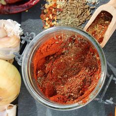 a glass bowl filled with spices next to garlic