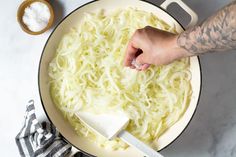 someone using a spatula to stir noodles in a pan