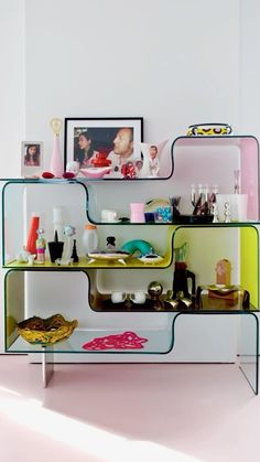 a shelf filled with lots of different items on top of a pink floor next to a white wall