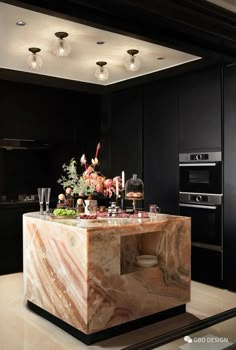 an elegant kitchen with marble counter tops and black cabinets is pictured in this image, there are lights above the island