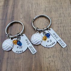 two personalized keychains with names and dates on them sitting on a wooden table