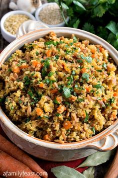 a bowl filled with rice, carrots and parsley on top of a table