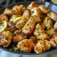 a pan filled with chicken and lemons on top of a stove burner covered in seasoning