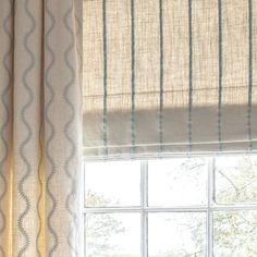 a cat sitting on top of a window sill next to a window with curtains