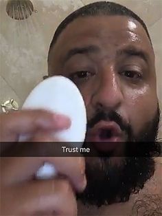 a man is brushing his teeth in the bathroom with soap on his face and looking at the camera