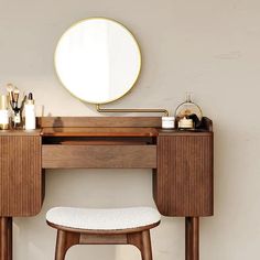 a wooden desk with a mirror and stool in front of it next to a wall