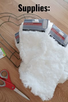 supplies laid out on top of a wooden table with scissors and yarn in the background