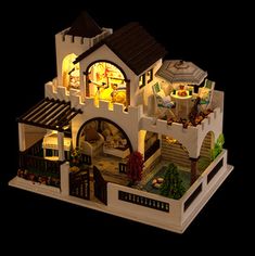 a toy house with lights and furniture on top of a wooden floor next to a wall