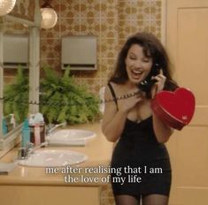 a woman holding a red heart in front of a bathroom mirror