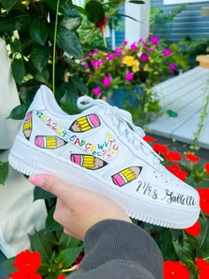 a person holding up a white shoe with colorful crayons on it