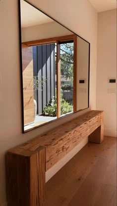 a wooden bench sitting under a large mirror