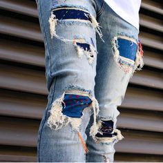 a person wearing ripped jeans with holes in the bottom and sides, standing next to a building