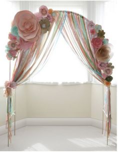 the wedding arch is decorated with pink flowers and ribbons on it's headboard