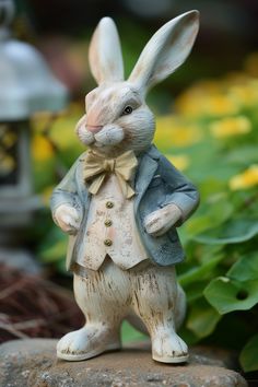 a statue of a rabbit dressed in a suit and bow tie standing on a rock