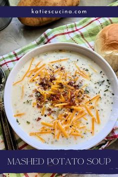 a bowl of mashed potato soup with cheese on top and bread in the background