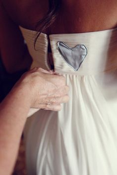 a woman in a white dress with a silver heart on it's back pocket