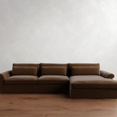 a brown couch sitting on top of a hard wood floor next to a white wall