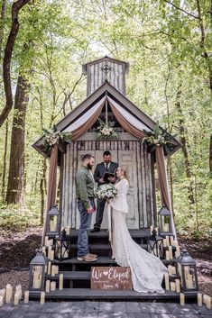 a couple getting married in front of a small wooden structure with candles on the steps