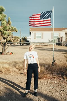 a woman standing in front of a fence with an american flag on the back of her shirt