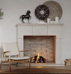 a living room with a fire place next to a chair and vase on the wall