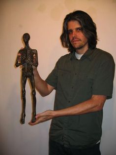 a man is holding up a statue of a person with a human figure in his hand