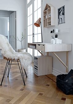 a white chair sitting on top of a hard wood floor next to a desk and mirror