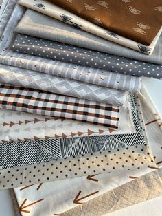 a pile of different types of fabric sitting on top of each other in front of a white table